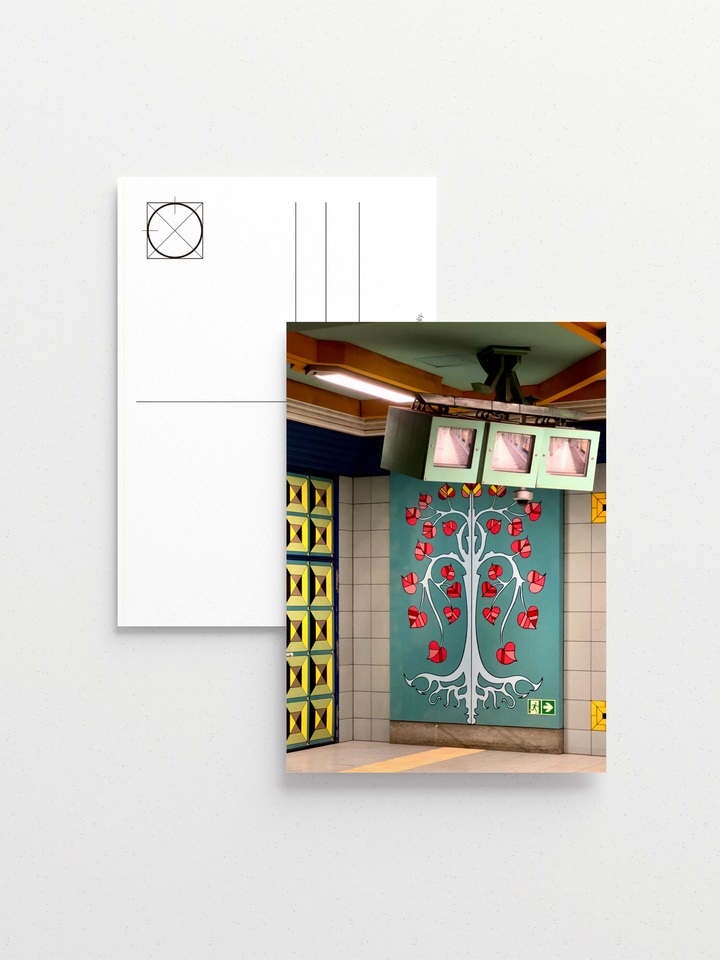 Hand-stamped station name and vivid mural of a beech tree on Berlin U-Bahn tiles.